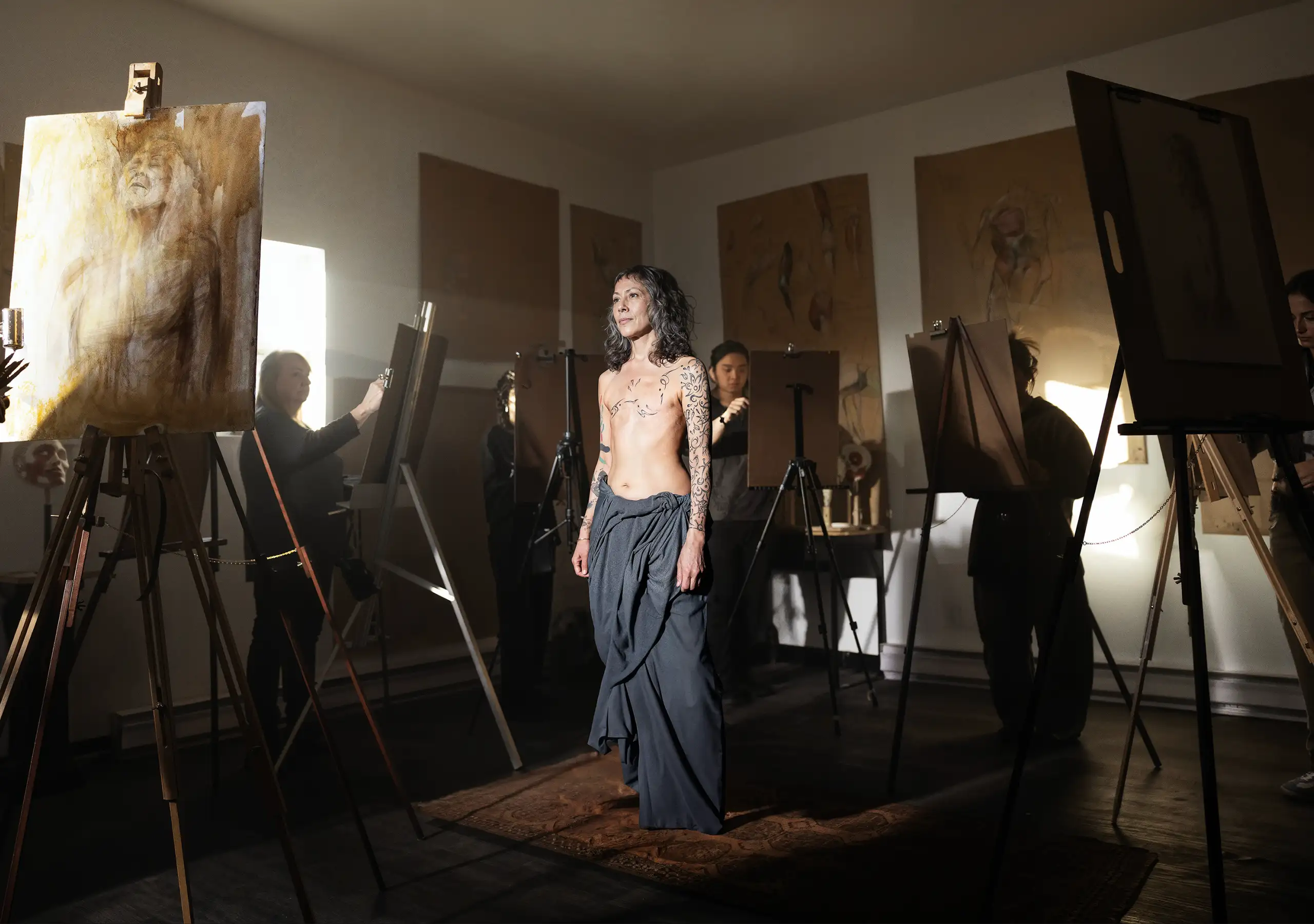 Mika posing in the studio surrounded by artists at their easels